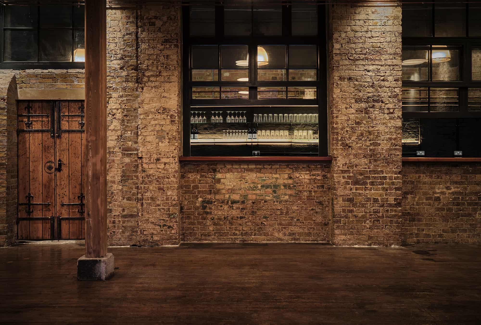 The bare brick room and its built-in bar hatch, low lit